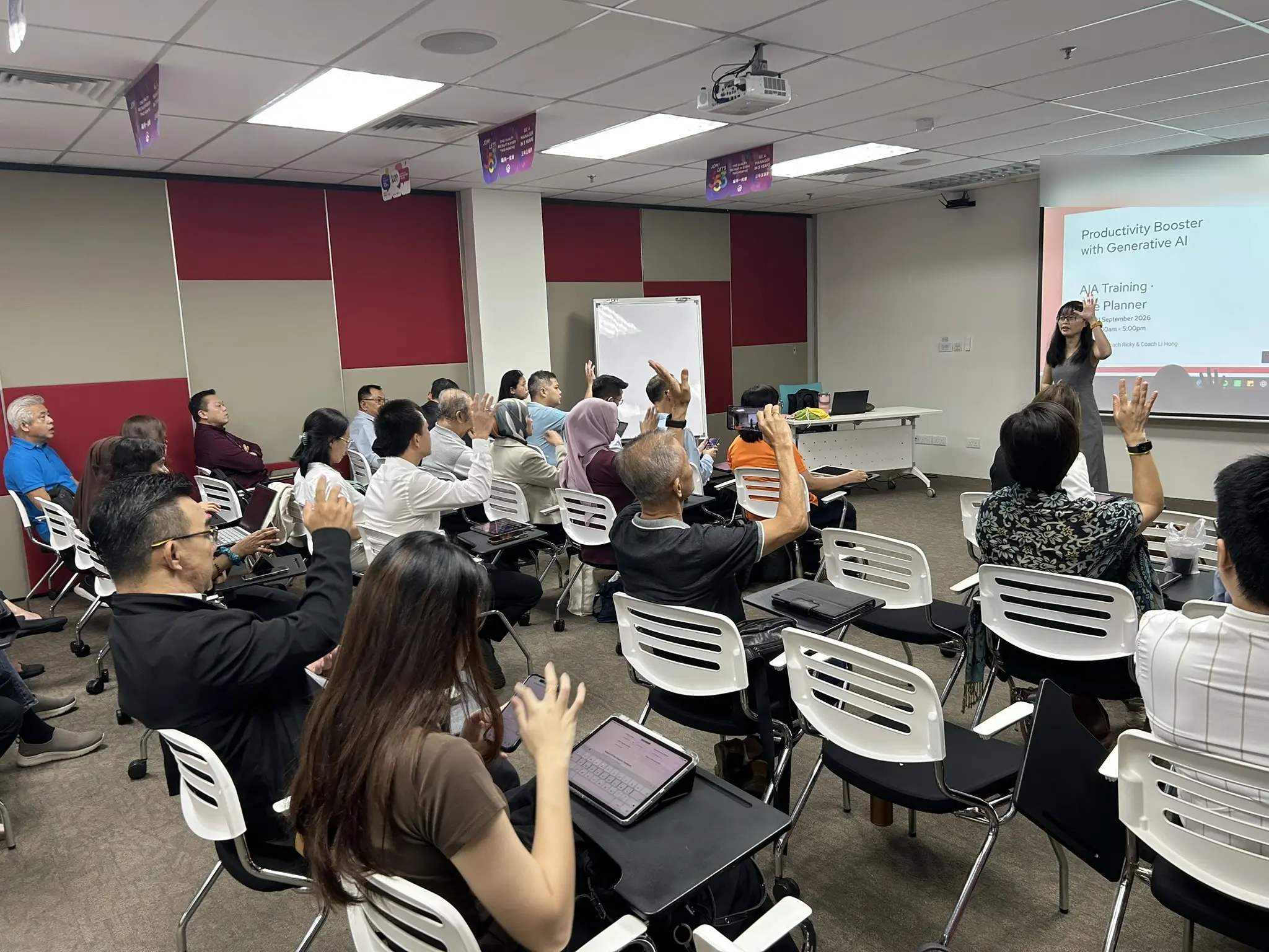Advisors seated in rows raising their hands while a trainer speaks at the front of a training room in Penang, 21 September 2026