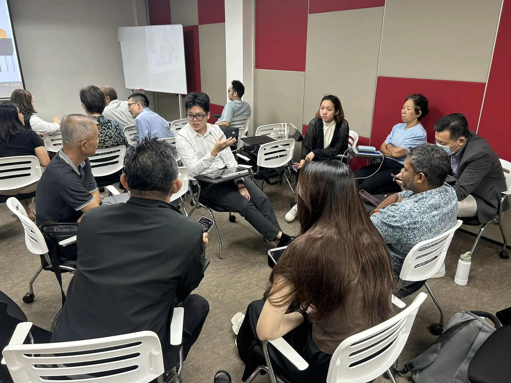 Advisors sitting in a loose circle of chairs talking to each other during a training session in Penang, 21 September 2026