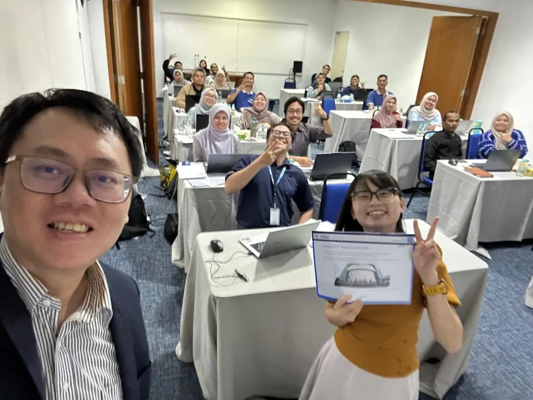 Trainer and participants at the ChatGPT Team Essentials corporate session, one holding up the course handout, 4 August 2025