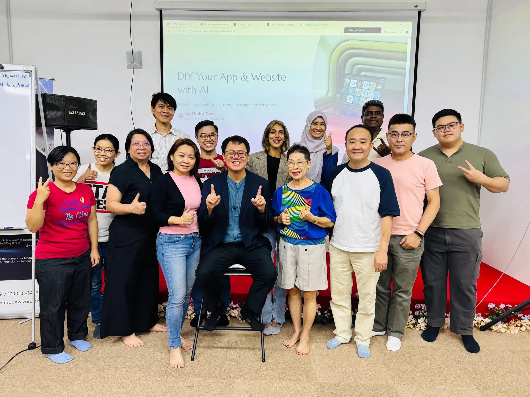 Group photo of participants with trainer Ricky Soo at the DIY Your App and Website with AI workshop, with the title slide on screen behind them