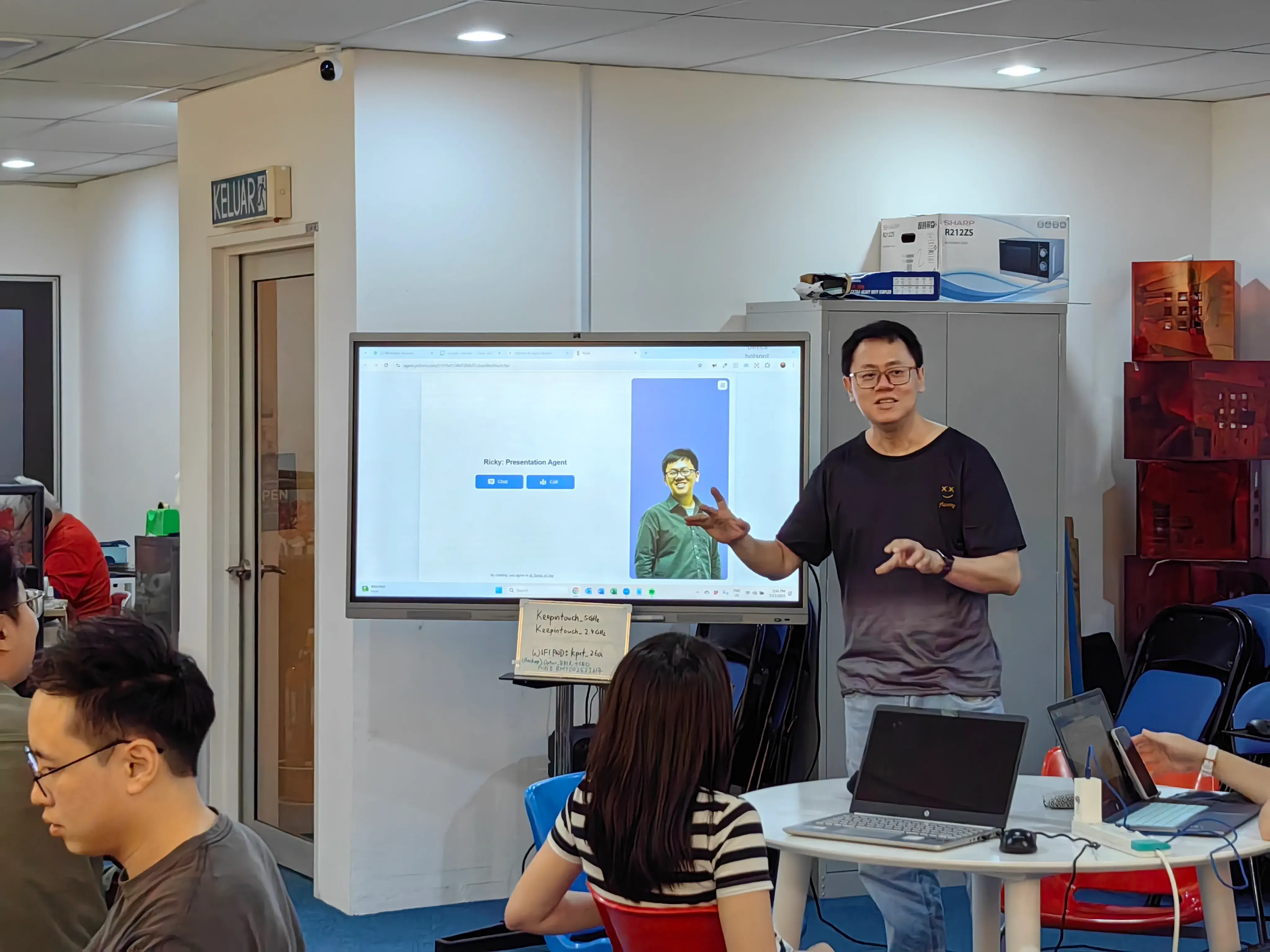 Speaker demonstrating a live presentation agent, its avatar and chat buttons on screen at Inno Day #1