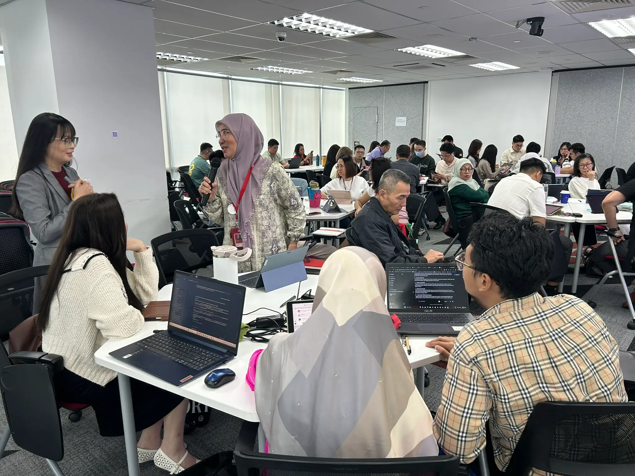 An advisor standing with the microphone to speak to the room while the trainer listens