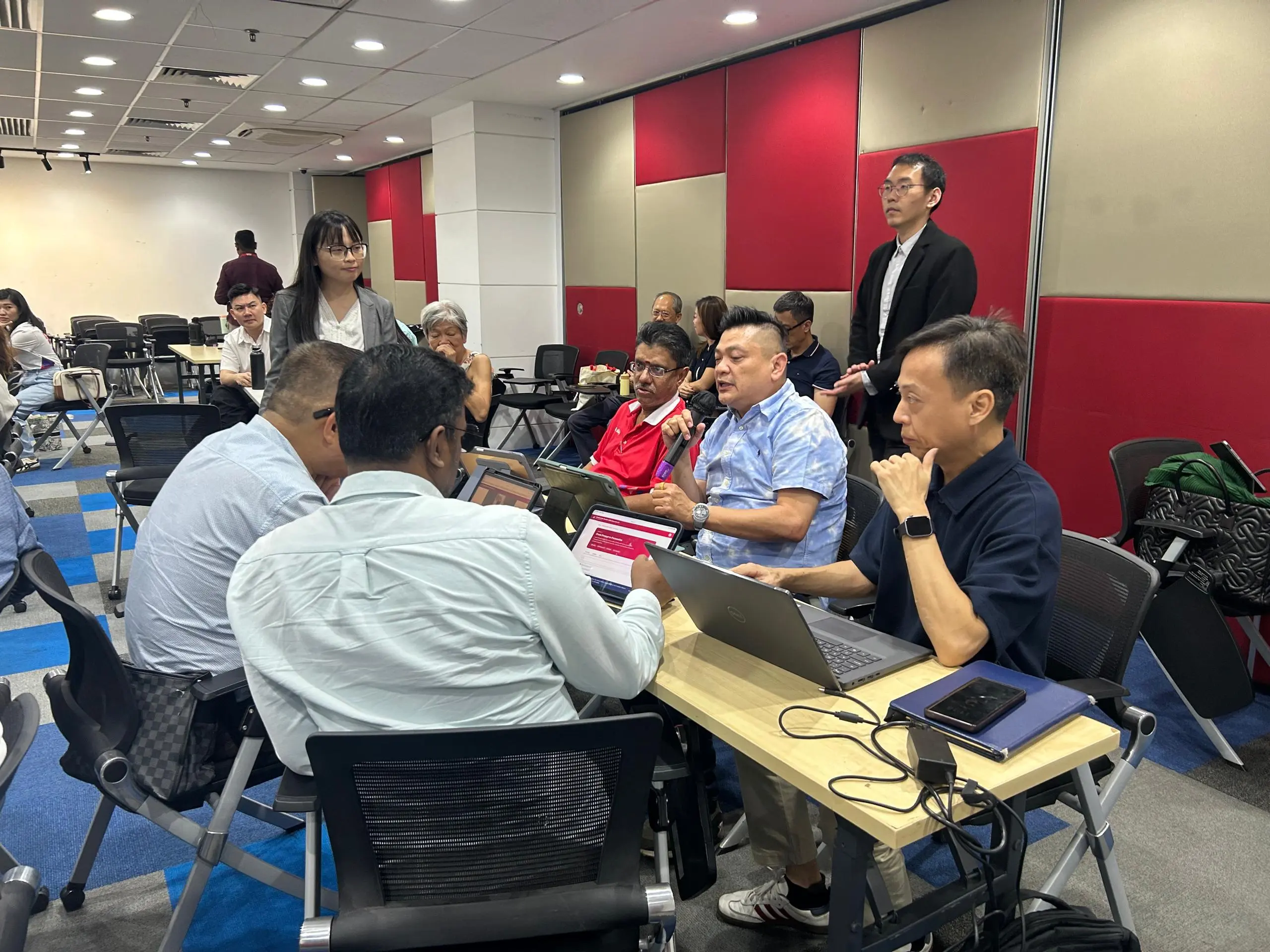 Another small group of advisors gathered around laptops, one holding the microphone to share