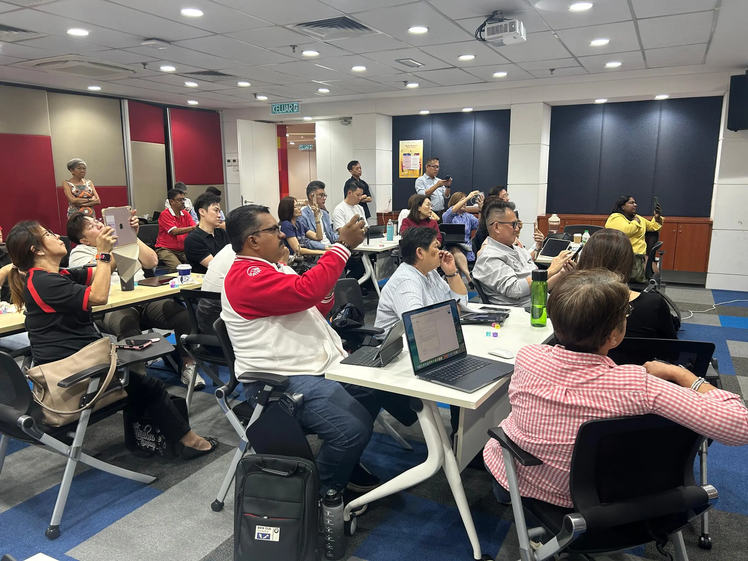 A room full of advisors holding up their phones at once to photograph the screen