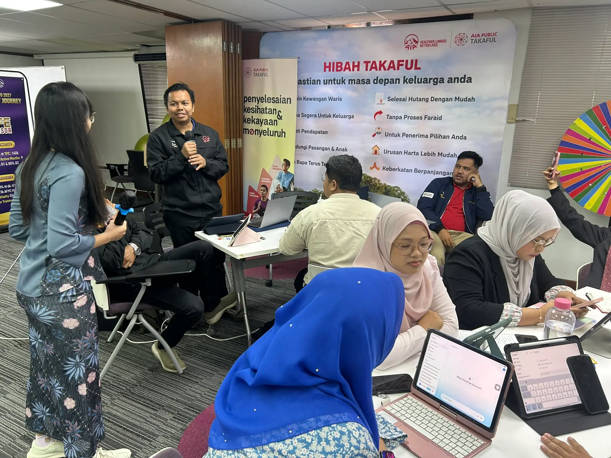 Seorang peserta memegang mikrofon sambil berdiri berkongsi dengan rakan-rakan sebilik