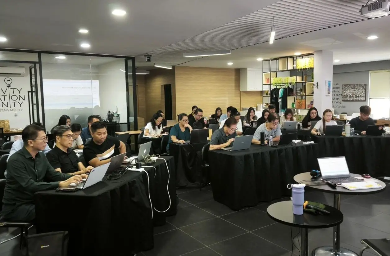 Wide view of the training room at GA Space, rows of participants at laptops with the projection screen to the left