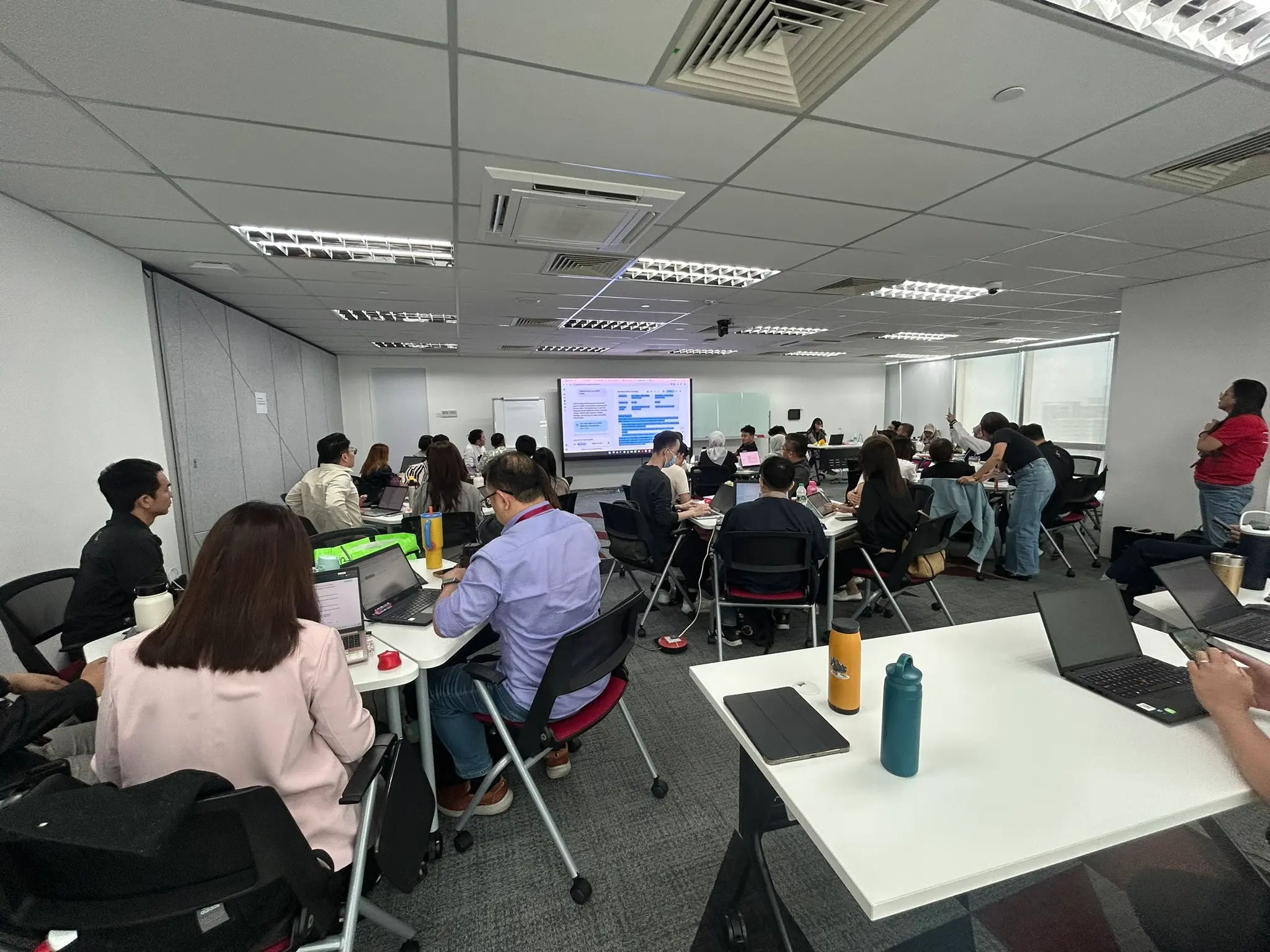 培训教室全景，学员各自在笔记本电脑前，投影幕在前方