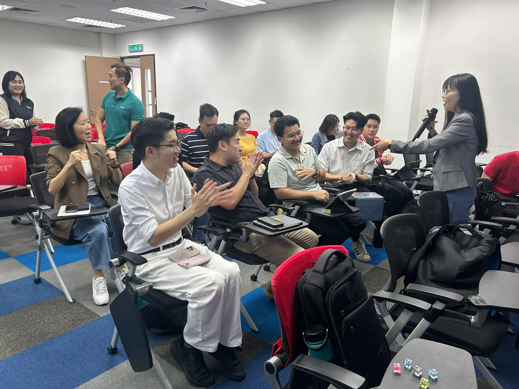学员们鼓掌，讲师拿着麦克风站在一旁