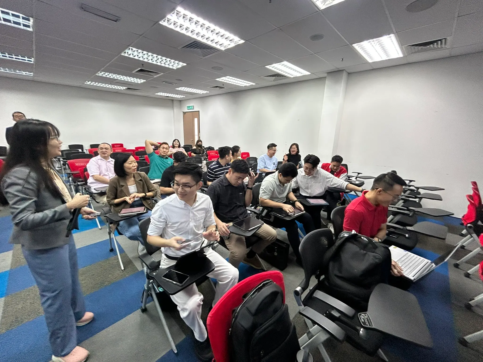 教室后半部，学员们坐在带写字板的座椅上边听边操作