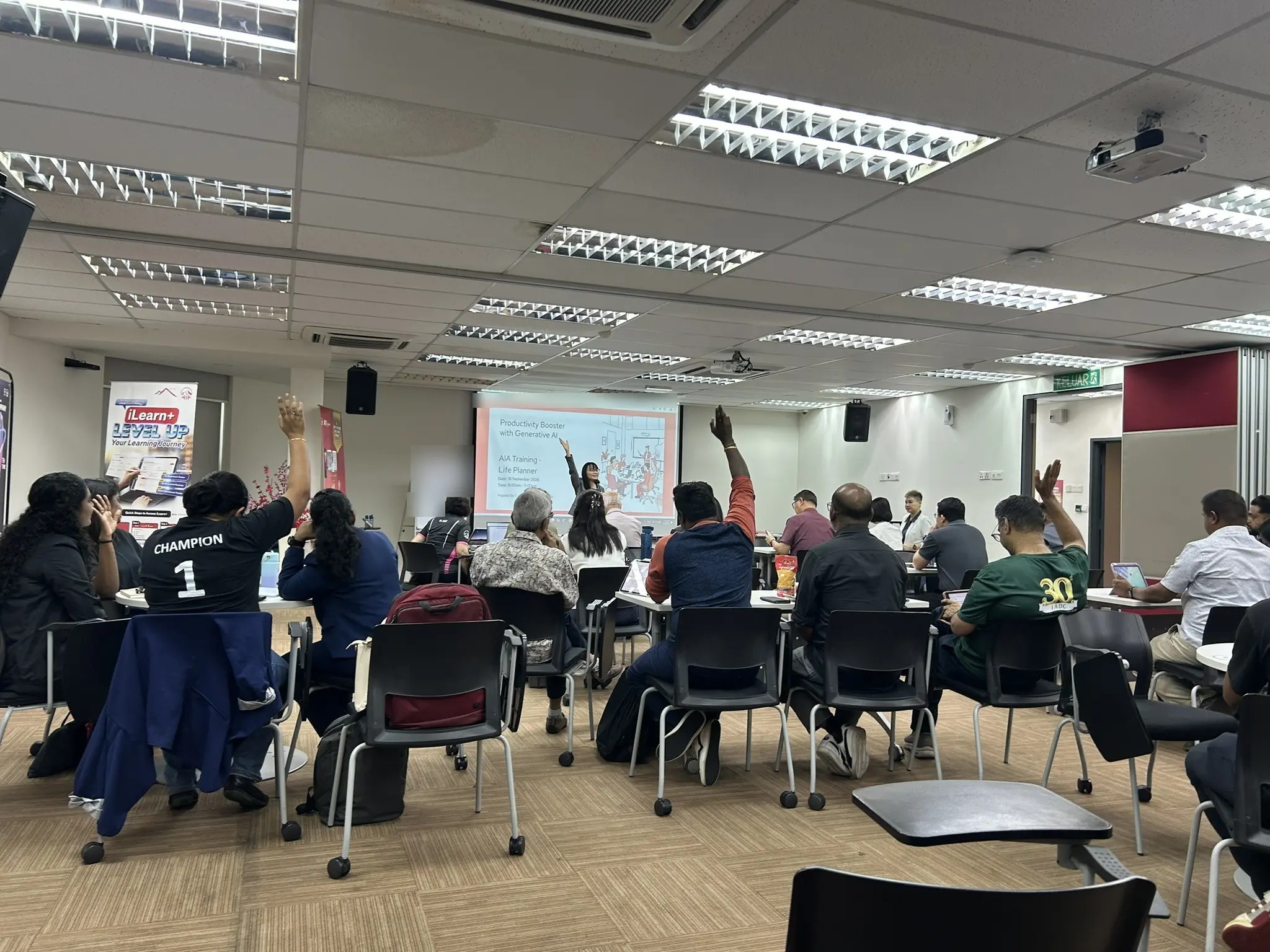 Advisors seated at round tables in a training room with several of them raising their hands to answer a question, Seremban, 18 September 2026
