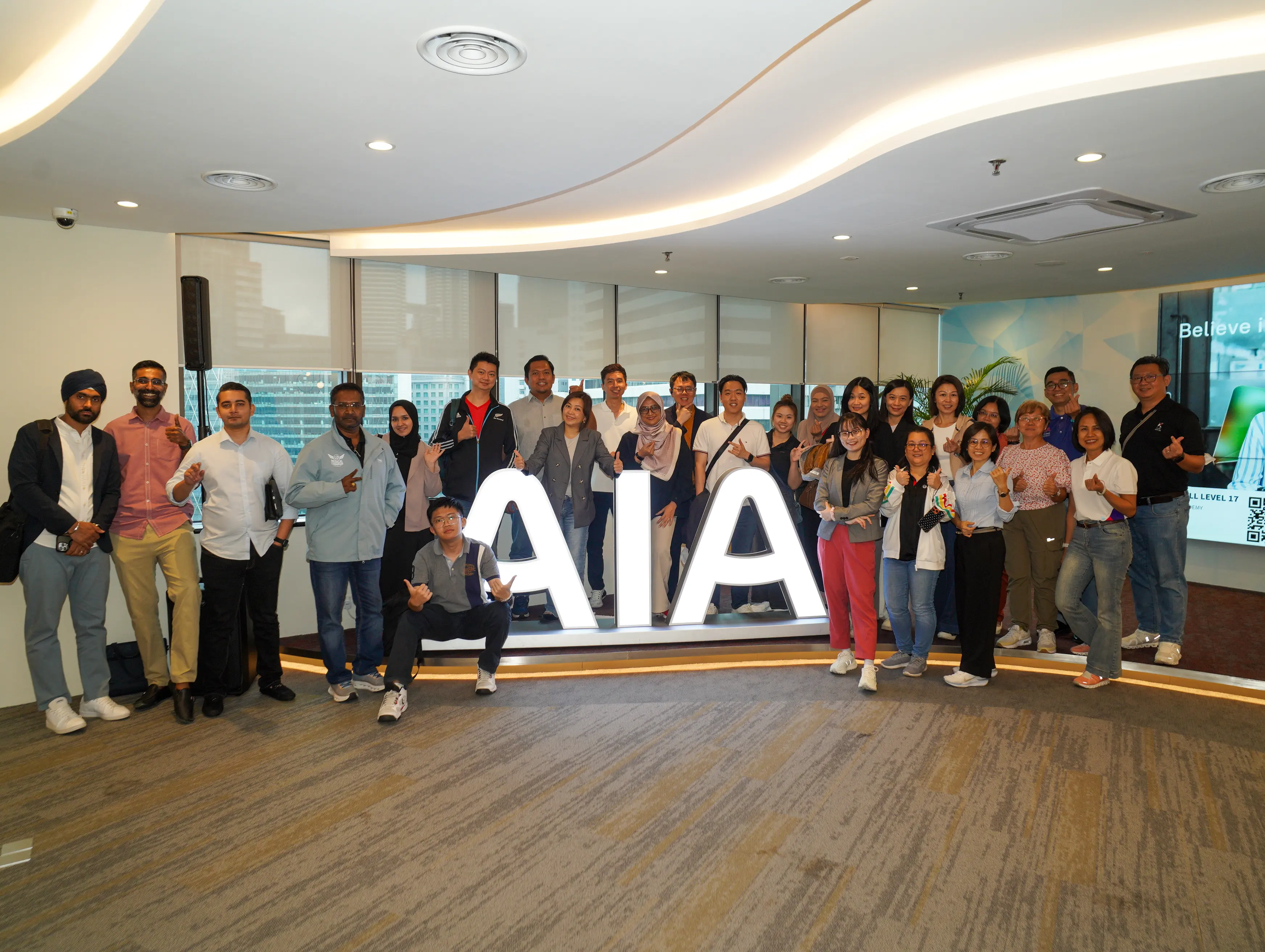 A large group of AIA advisors posing by the illuminated AIA sign after a full-day AI training session, 19 August 2026