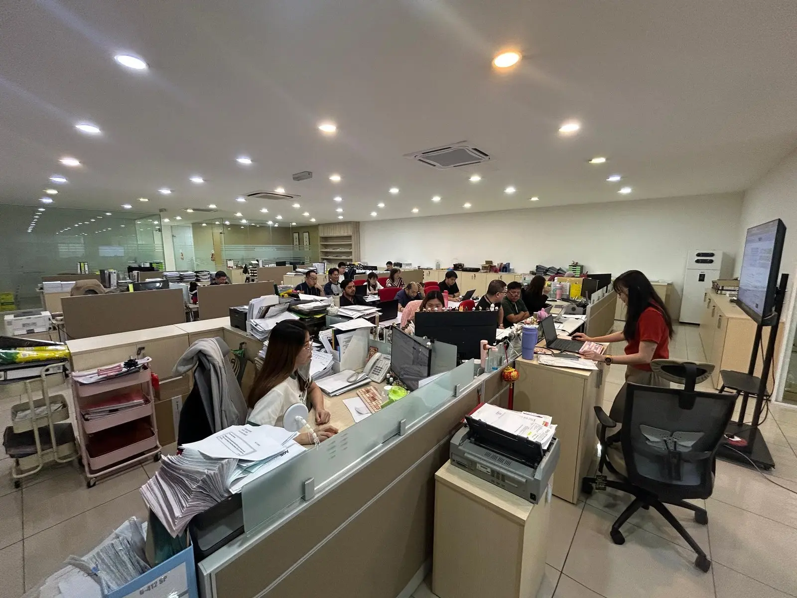 Participants at their workstations watching the training screen, files and paperwork still stacked around them