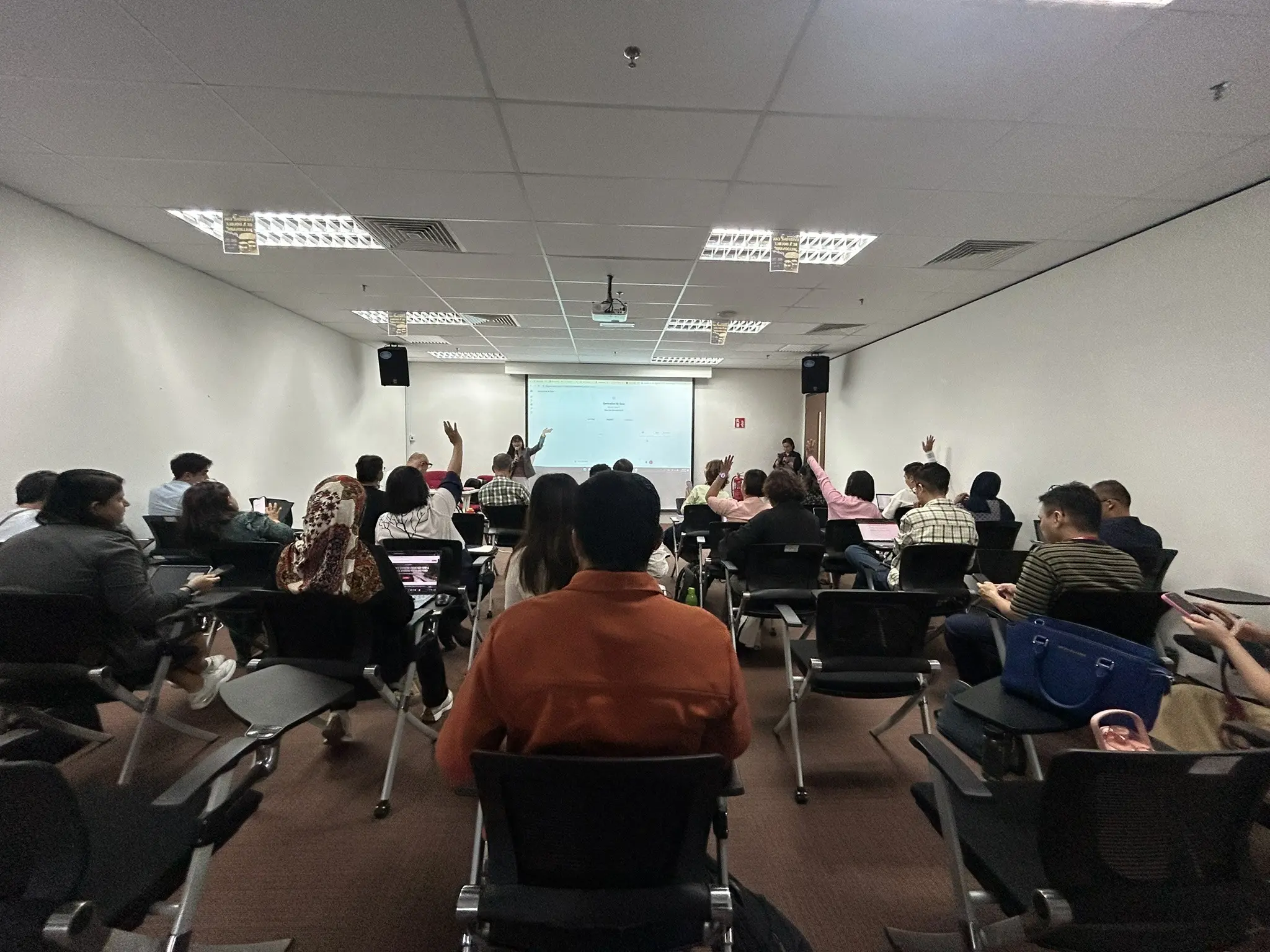 Several advisors raising their hands in answer to a trainer holding a microphone at the front of a training room in Petaling Jaya, 23 September 2026