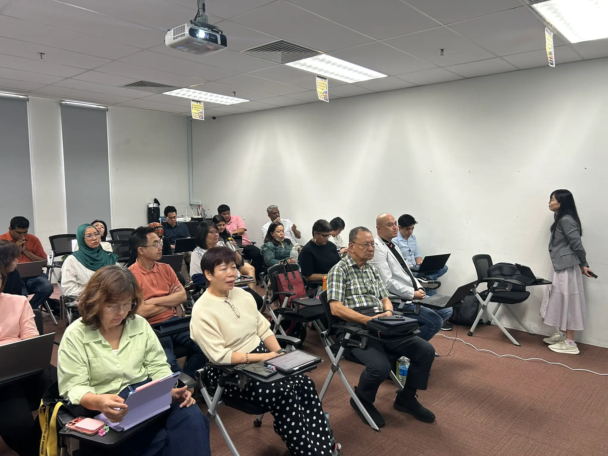Advisors seated with laptops and tablets on fold-out desks, listening as a trainer speaks from the side of the room, Petaling Jaya, 23 September 2026